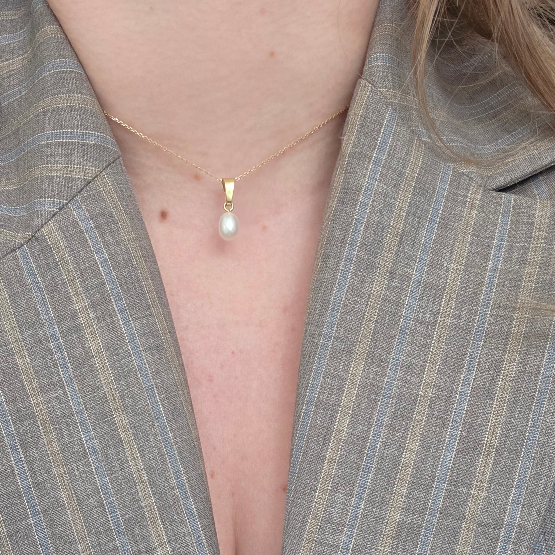 Close-up of a person wearing a gray suit with a visible tattoo on the arm.