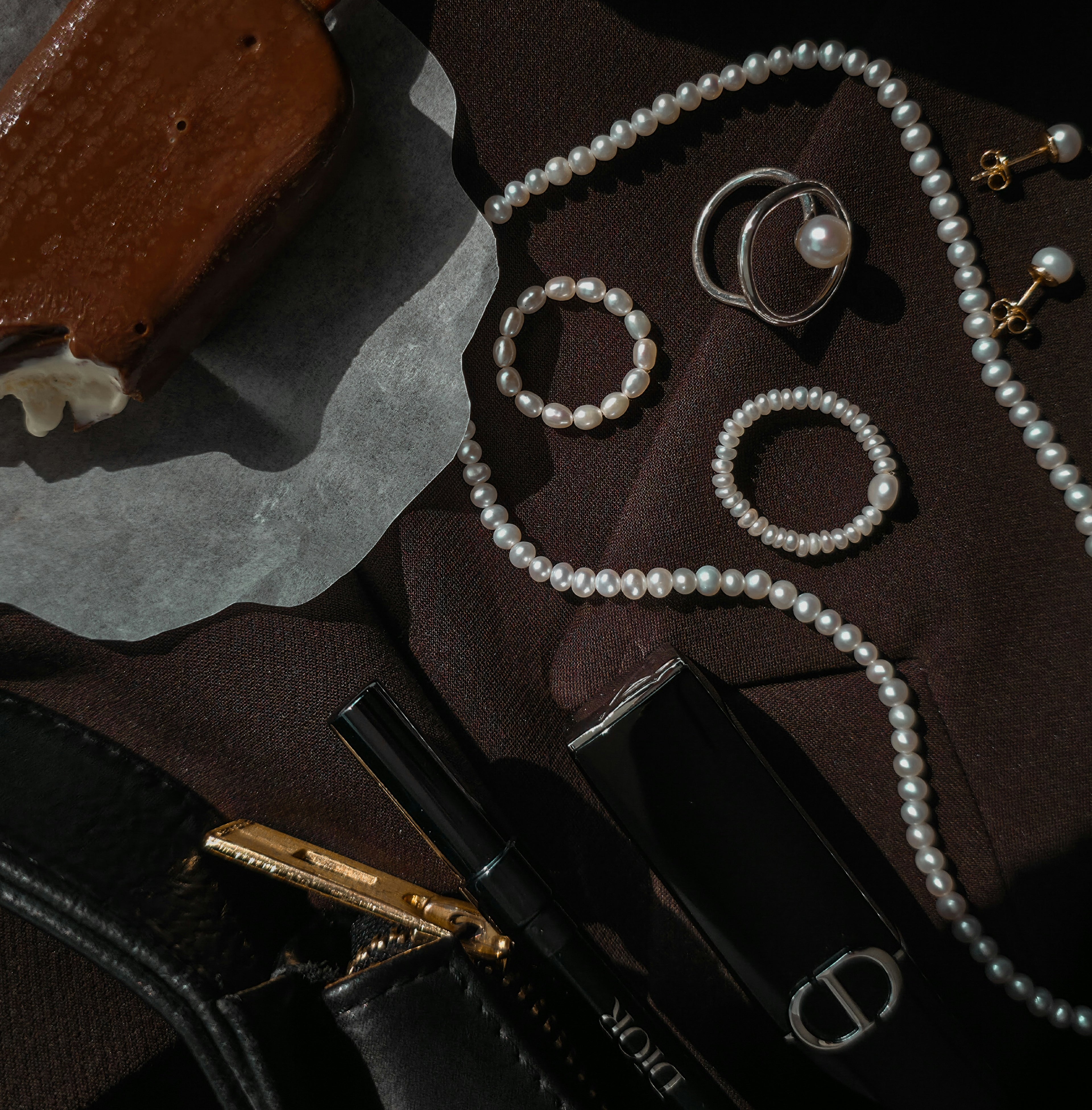 Pearl jewelry set with rings and necklace on a dark textured blazer. 