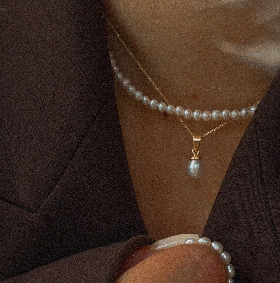 Pearl necklace and bracelet on a person wearing a brown garment