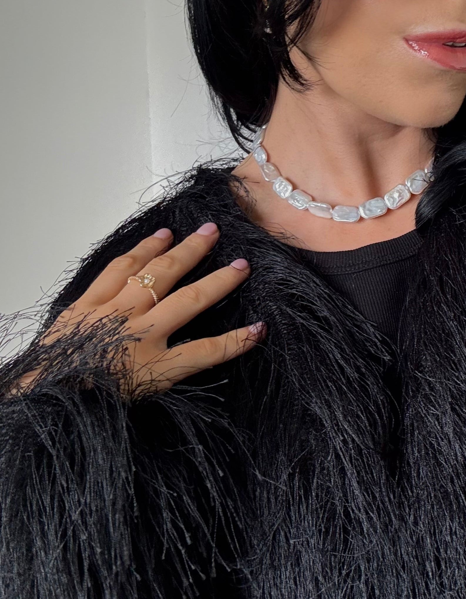 Person wearing a pearl necklace and sunglasses indoors.