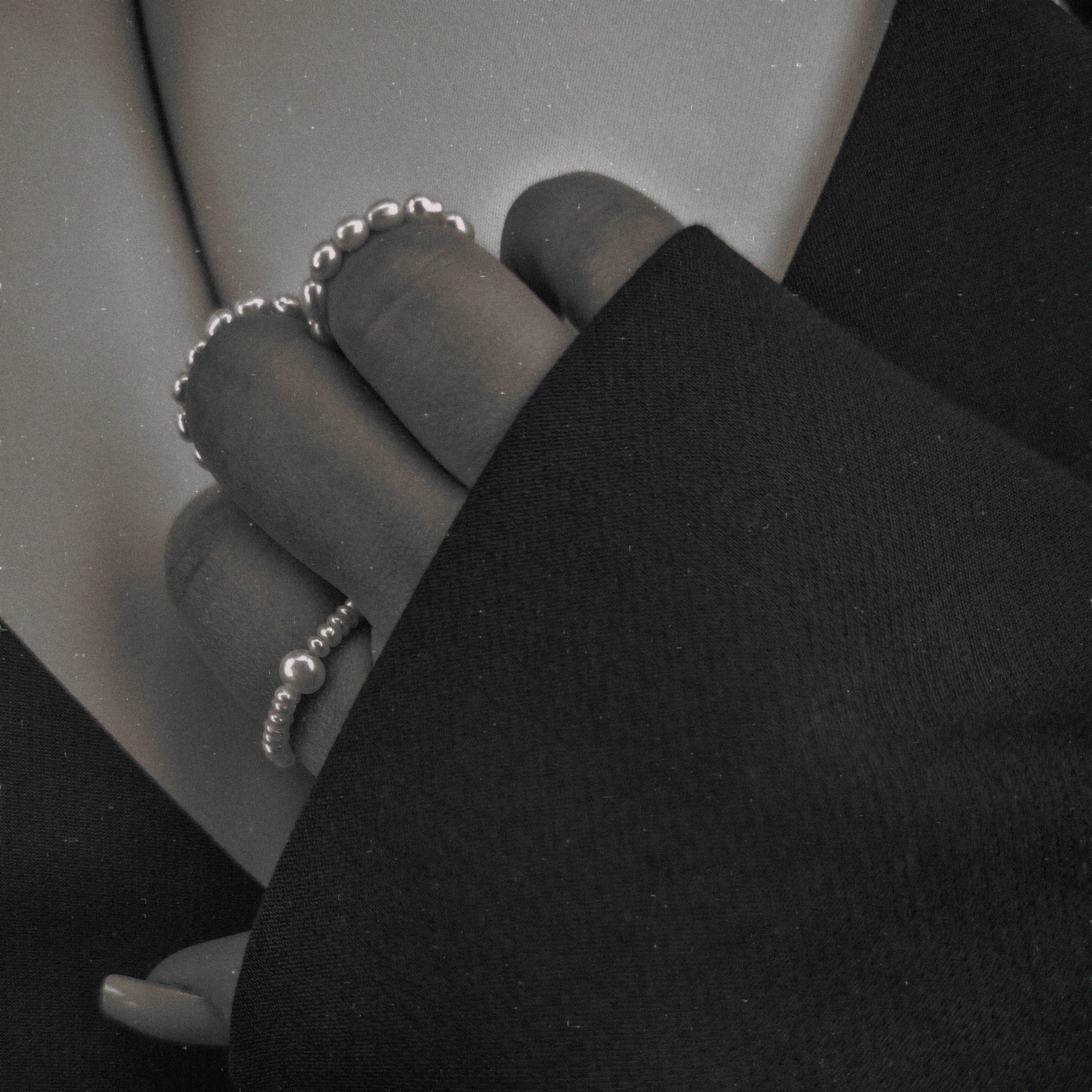 Close-up of a person wearing pearl rings on a plain background