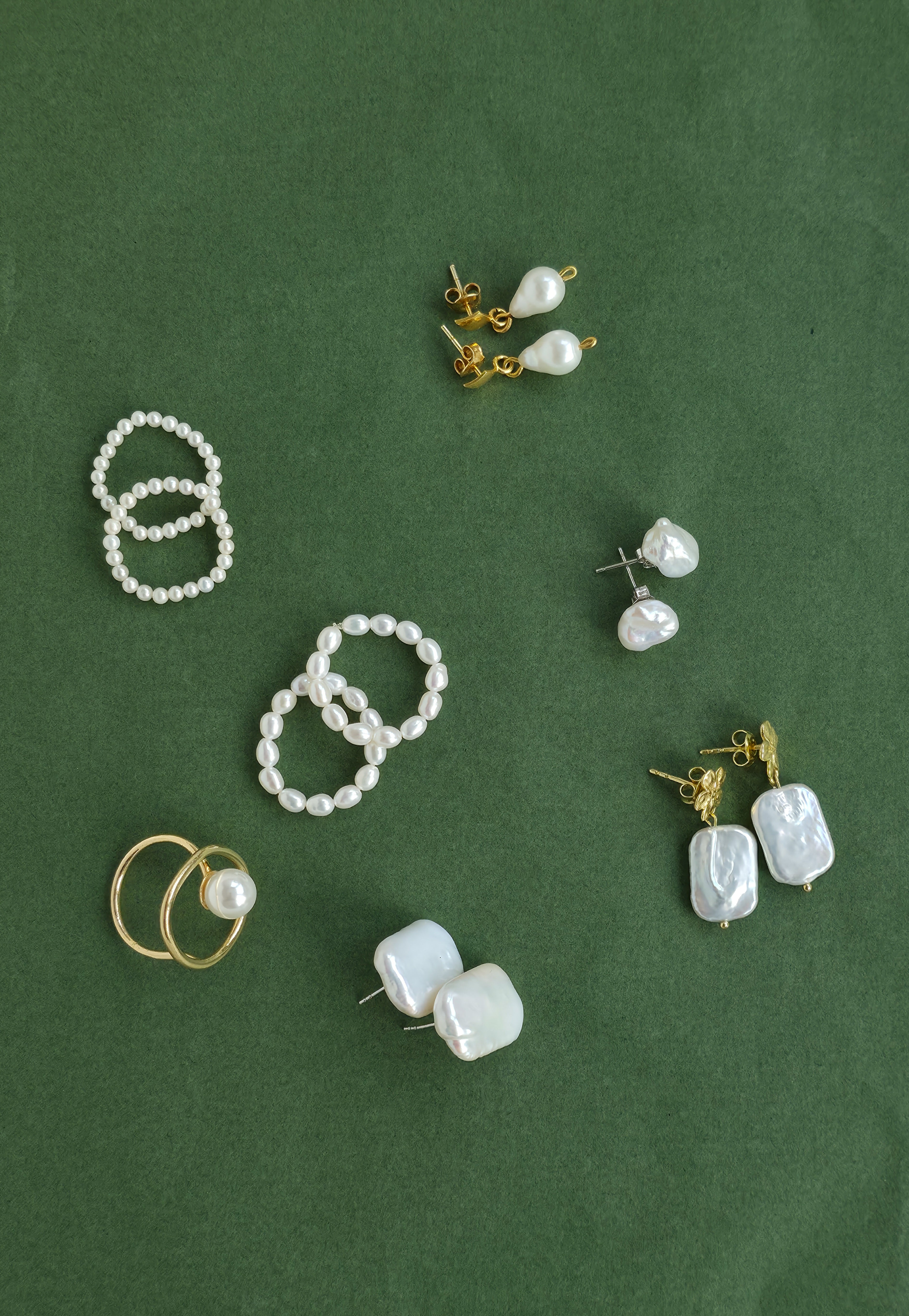 Collection of pearl earrings on a green background