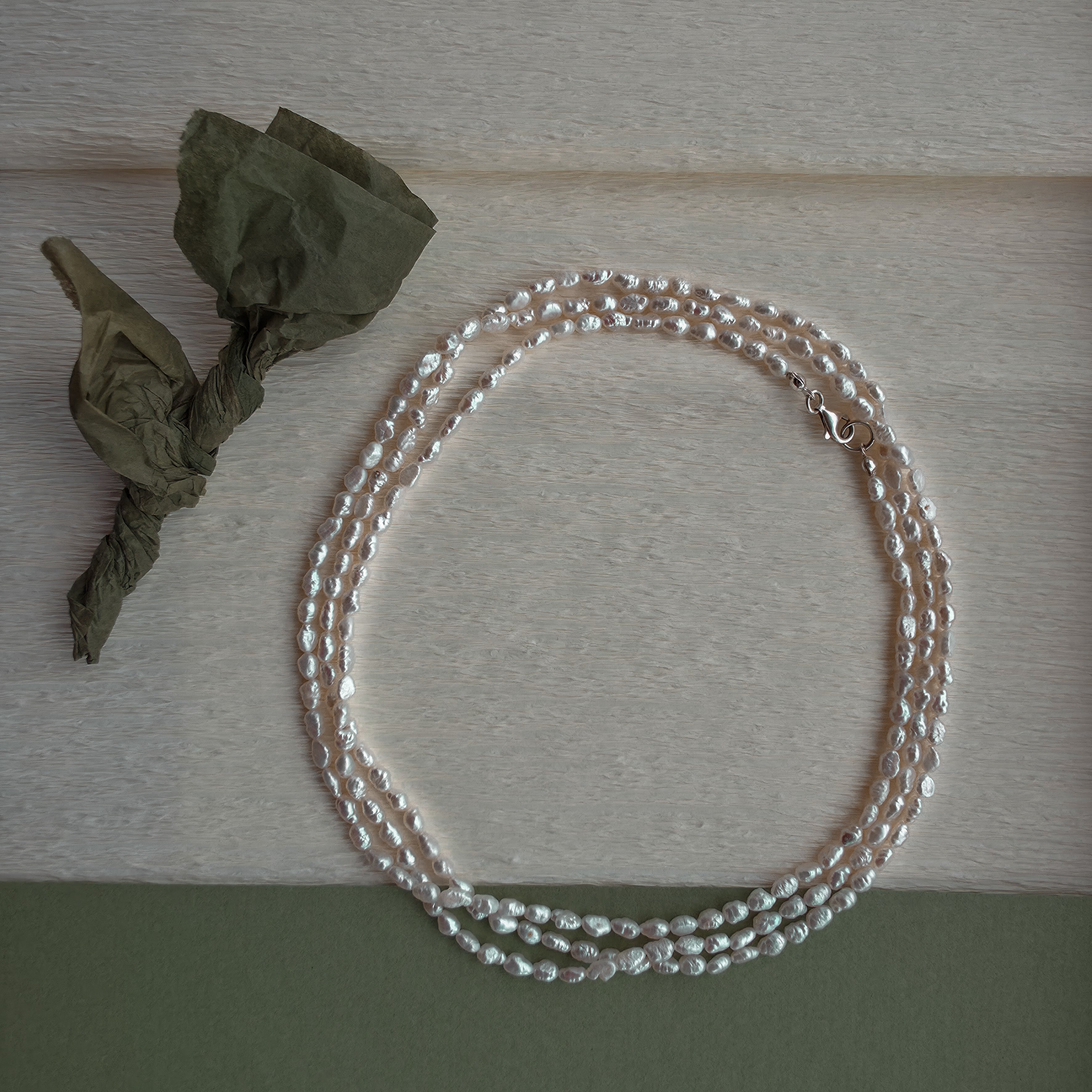 Pearl necklace on a wooden surface with dried leaves