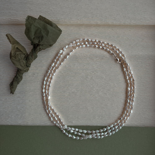 Pearl necklace on a wooden surface with dried leaves