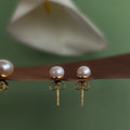Pearl earrings with gold posts on a green background