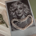 Pearl necklace draped over a black and white portrait of a woman with blonde hair.