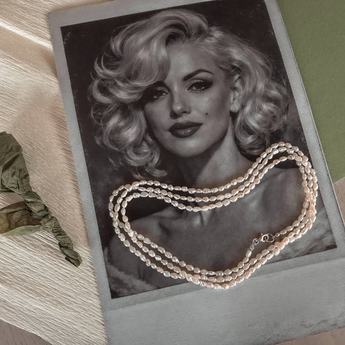 Pearl necklace draped over a black and white portrait of a woman with blonde hair.