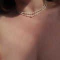 Pearl necklace on a person's neck with a neutral background