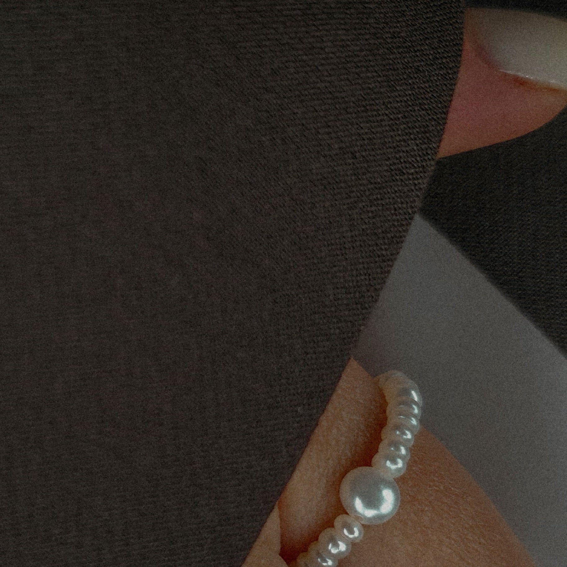 Close-up of a hand wearing a pearl ring with a pearl on a dark background
