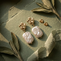 Gold floral earrings with pearls on a green leafy background