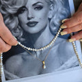 A layered Pearl necklace held over a black and white photo of a woman
