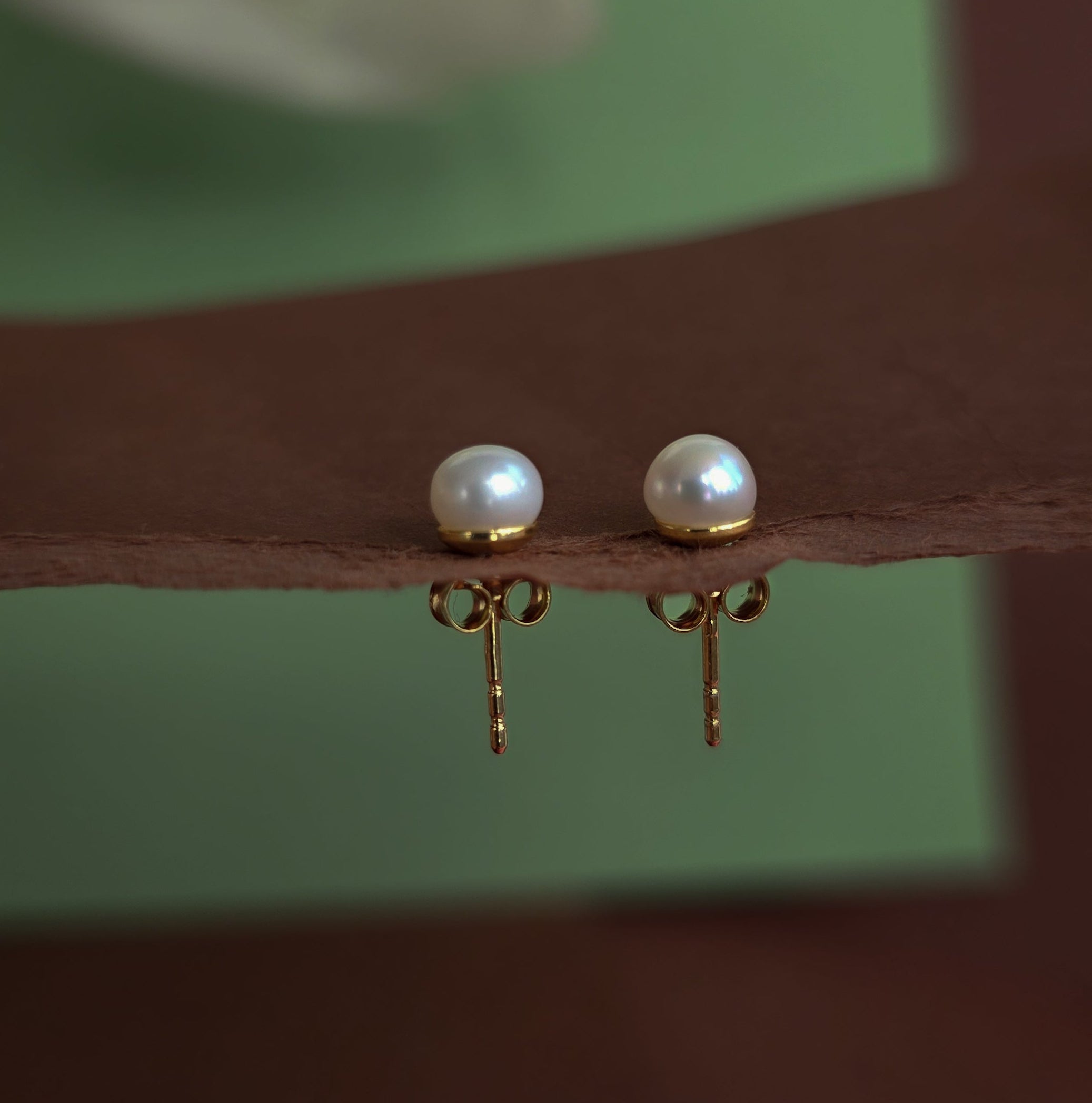Pearl earrings on a reflective surface with a blurred background