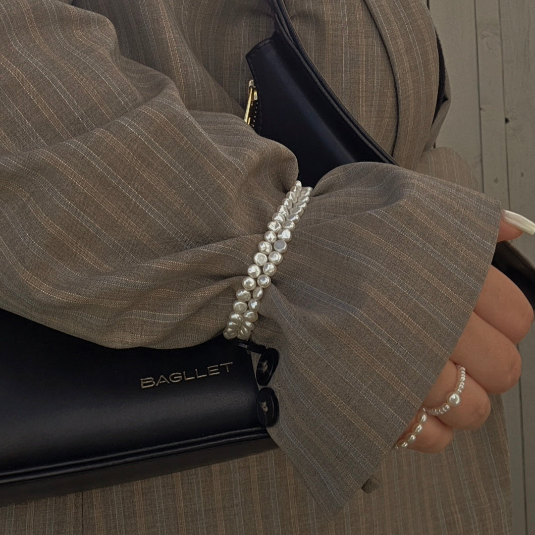 Person holding a black bag wearing midi rings with a blurred background