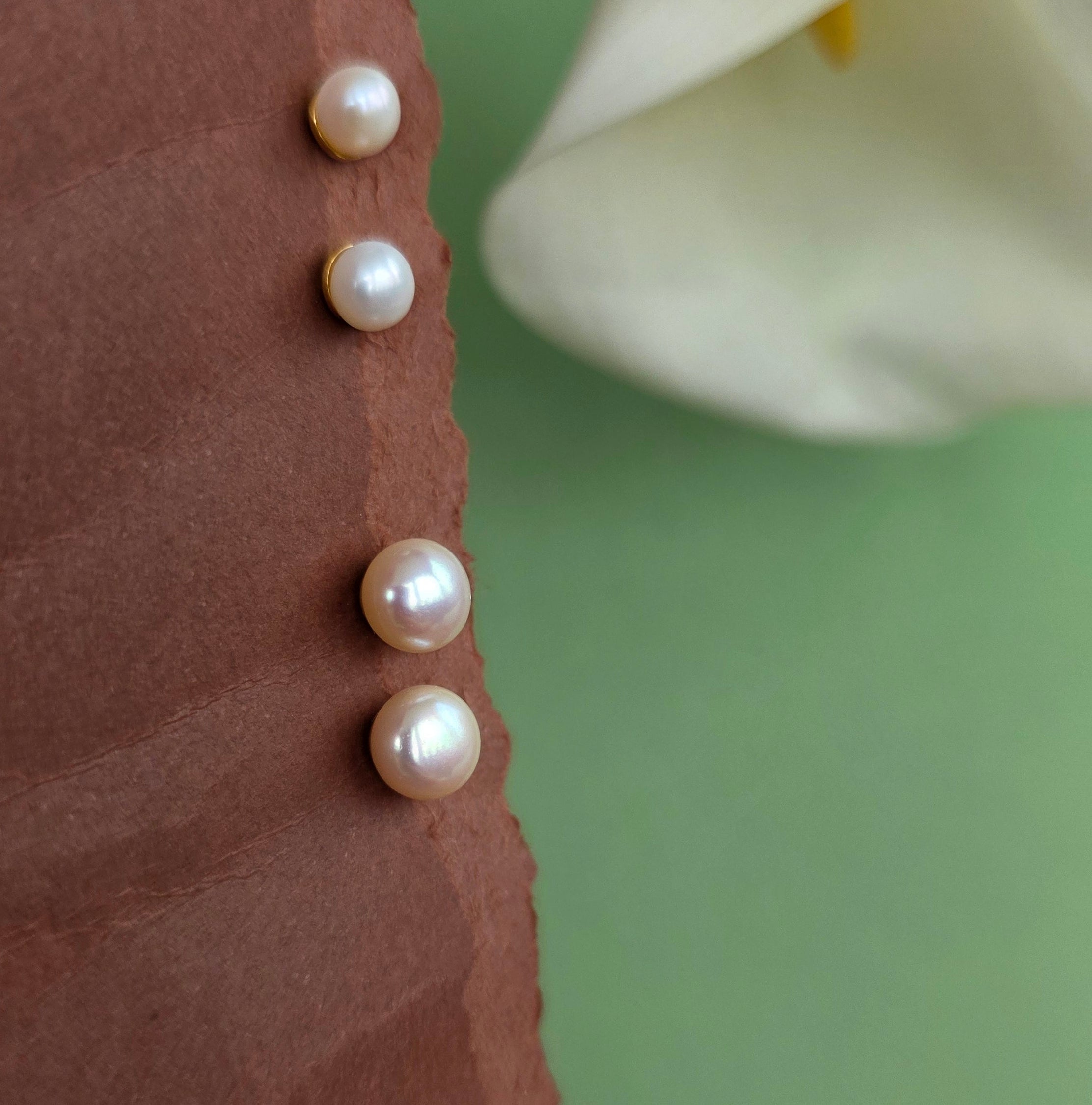 Pearls arranged on a textured surface with a white flower in the background