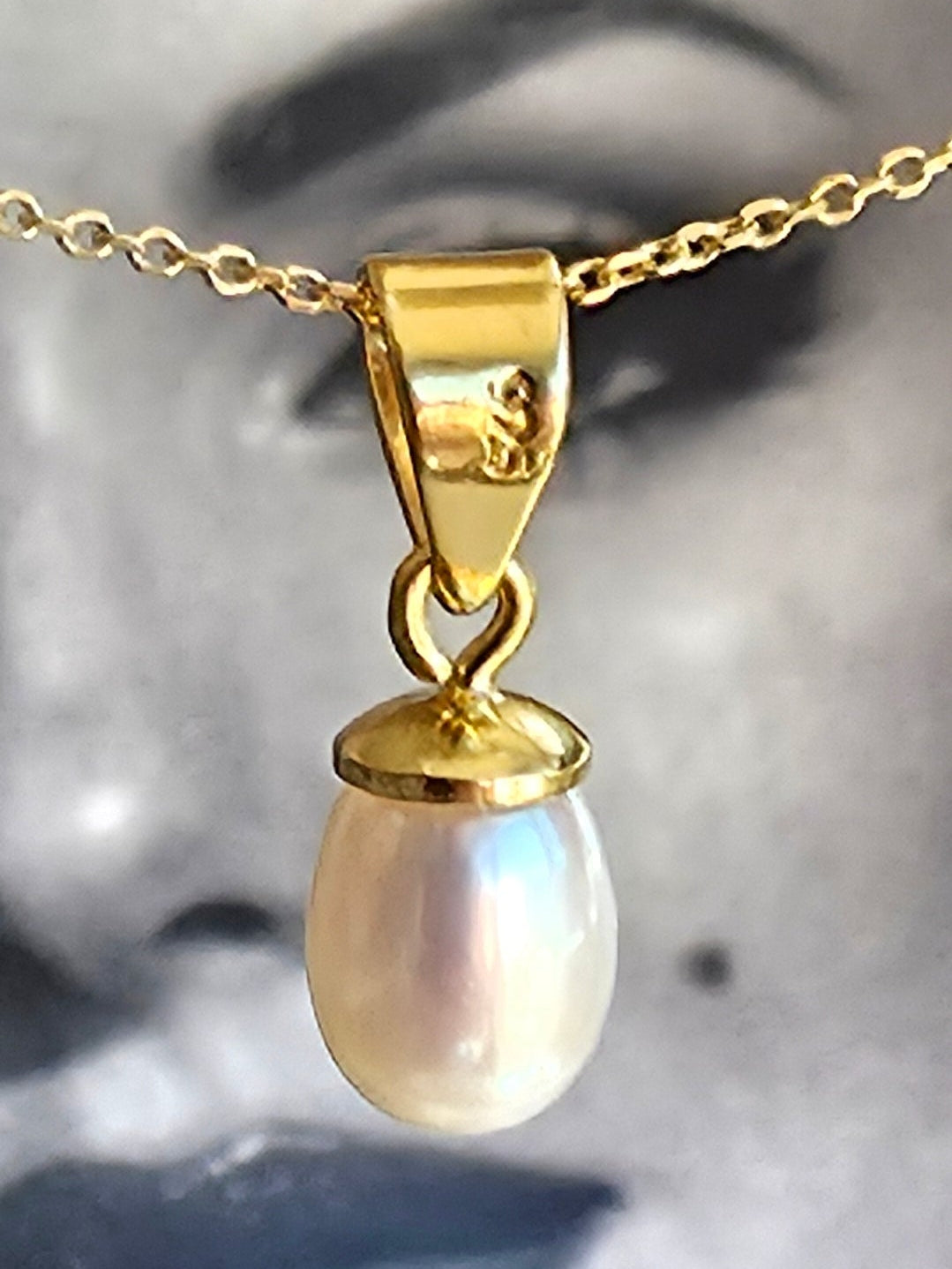 Gold pendant with a pearl on a blurred background