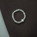 Pearl ring on a textured dark surface.
