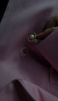 Close-up of a pearl ring on a dark fabric surface placed near a set of pearl midi rings.